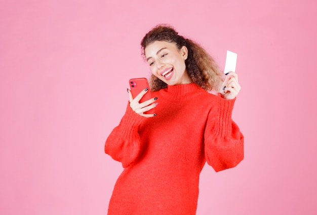 Free photo woman holding a business card and calling the number on it.