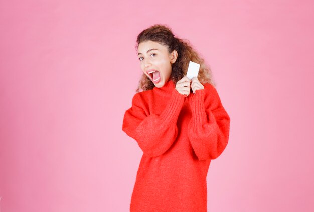 woman holding a business card looks very happy and surprized.