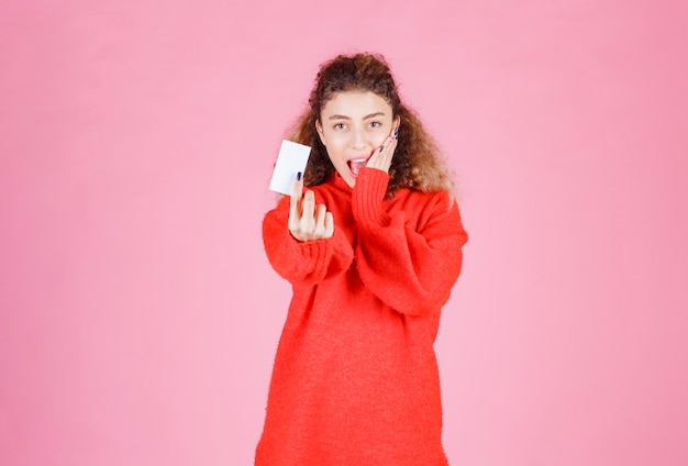 woman holding a business card looks very happy and surprized.