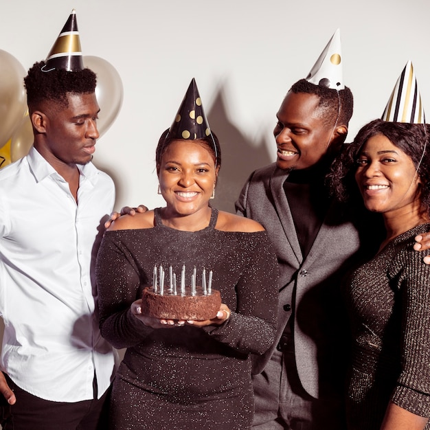 Woman holding a cake surrounded by friends