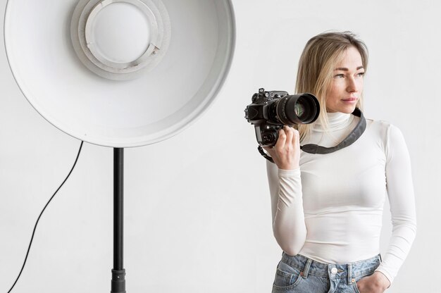 Woman holding a camera photo next to a studio lamp