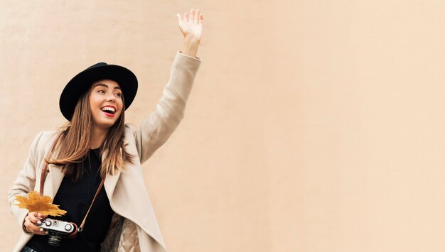 Woman holding a camera while one of her hands is raised