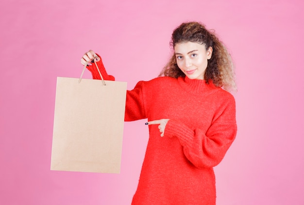 woman holding a cardboard shopping bag and looks satisfied.