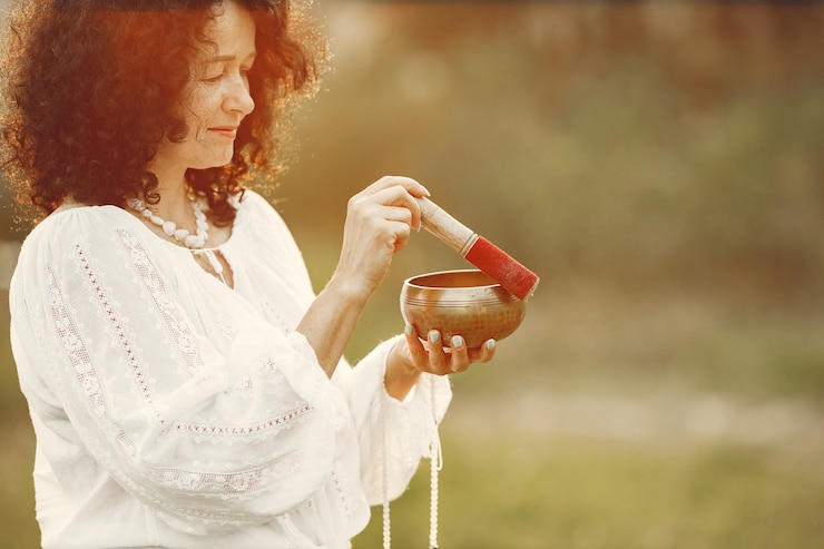 Free Photo woman holding chanting bowl in nature setting