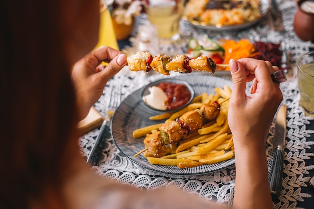 Woman holding chicken pieces on skewers sprinkled with sesame