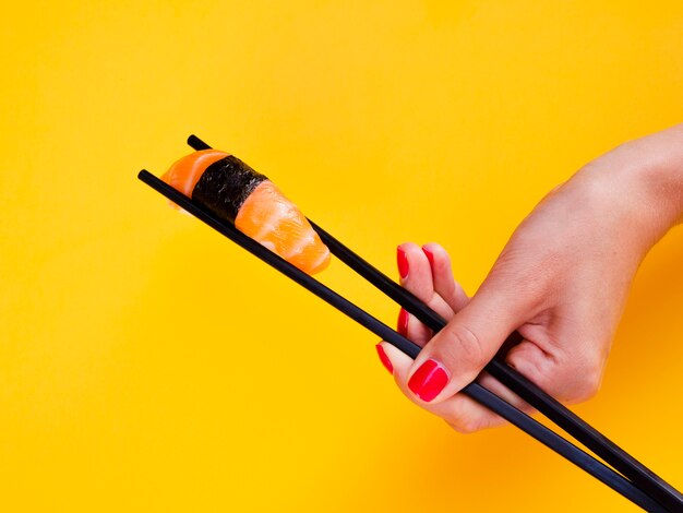 Woman holding in chopsticks a salmon sushi