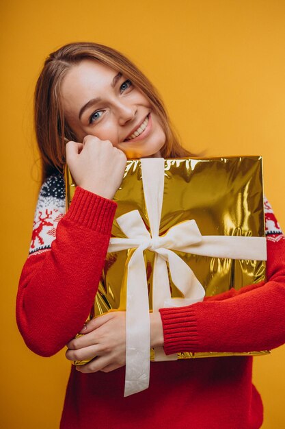 Woman holding christmas present on yellow
