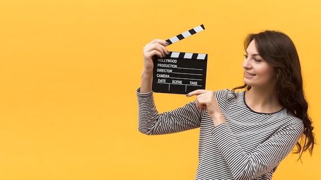 Woman holding a clapperboard next to her