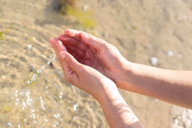 彼女の手で澄んだ水を保持している女性