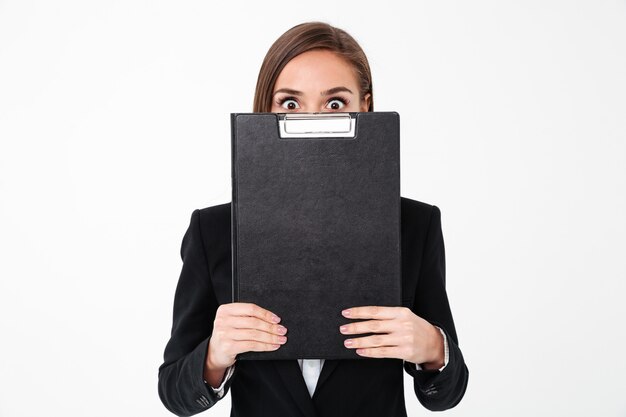 Woman holding clipboard covering face.