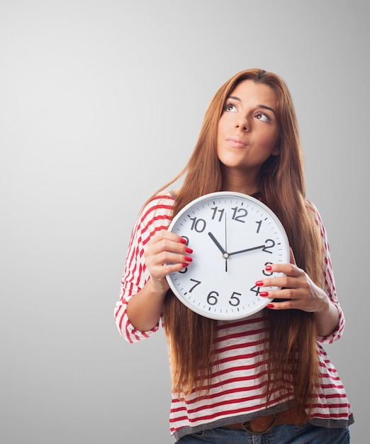 Woman holding a clock thinking