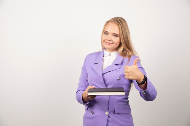 Woman holding closed tablet on white.