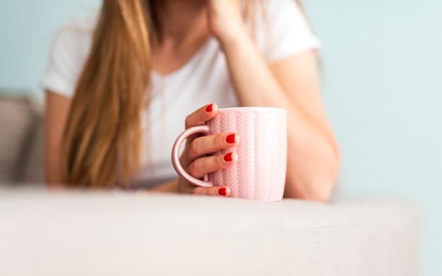 Free photo woman holding coffee cup on edge of sofa