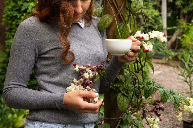 여자가 커피 컵과 꽃을 들고