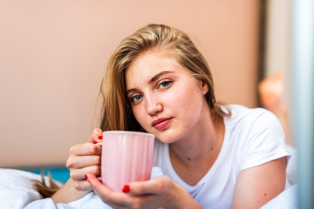 ベッドでコーヒーカップを保持している女性