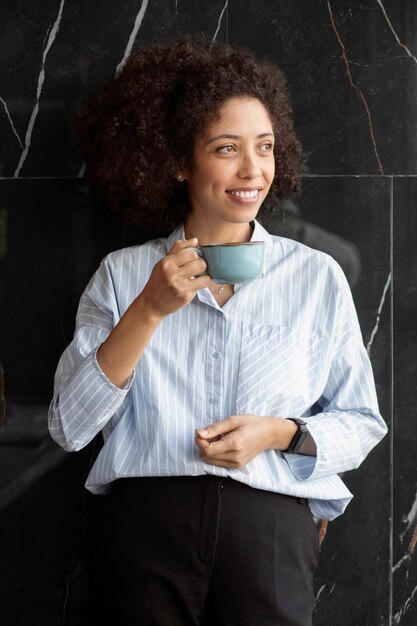 Foto gratuita tazza di caffè della holding della donna al colpo medio del lavoro