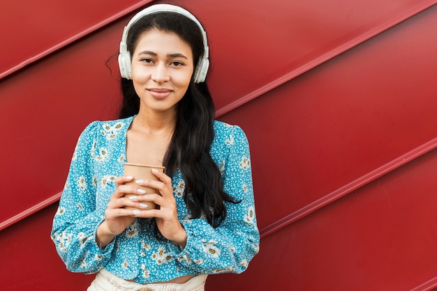 Free photo woman holding a coffee and having headphones