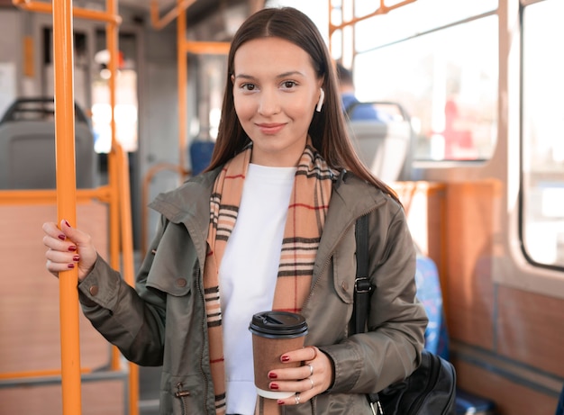 Woman holding a coffee in public tram transport