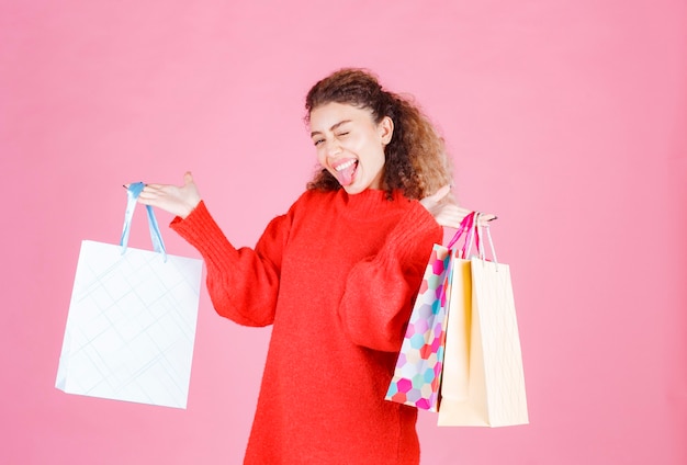 カラフルな買い物袋を持って幸せな気分の女性。