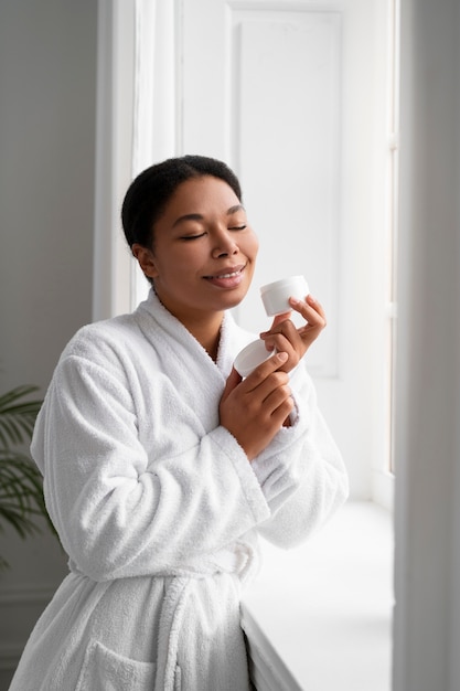 Free photo woman holding cream container medium shot