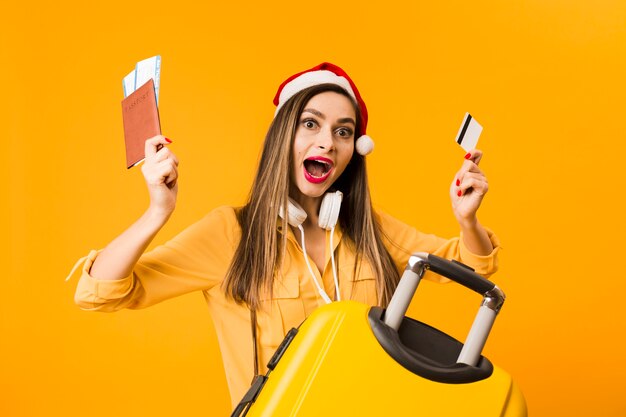 Бесплатное фото Женщина держит кредитную карту и билеты на самолет позирует рядом с багажом