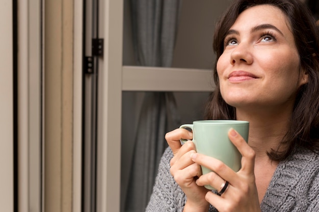 Woman holding a cup of coffee while looking up