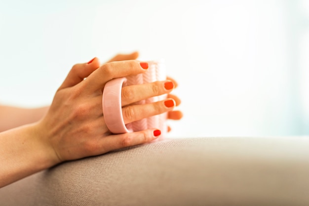 Free photo woman holding cup on sofa edge