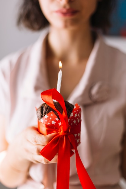 Woman holding cupcake tied with red ribbon bow