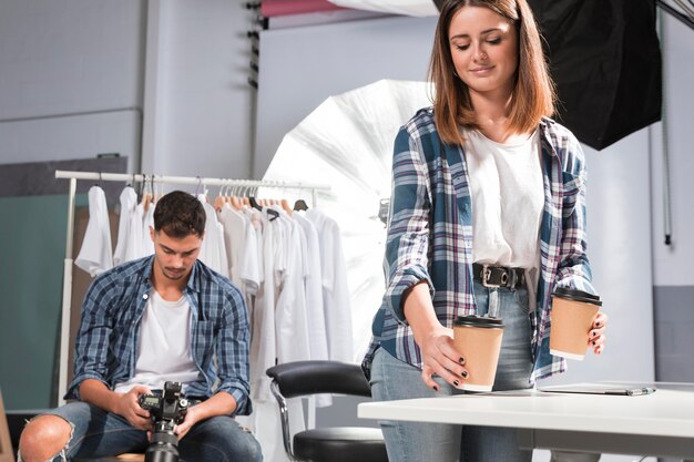 Woman holding cups of coffee next to photographer