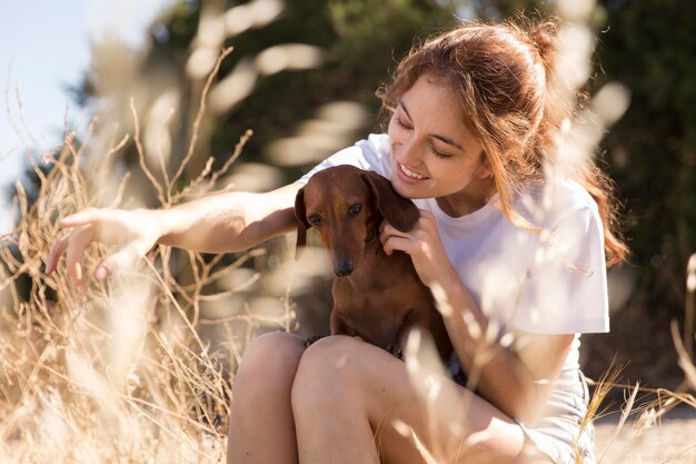 かわいい犬のミディアムショットを保持している女性