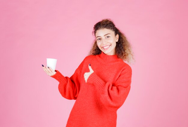 woman holding a disposable coffee cup and enjoying the taste.