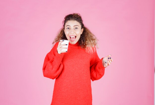 woman holding a disposable coffee cup and enjoying the taste.