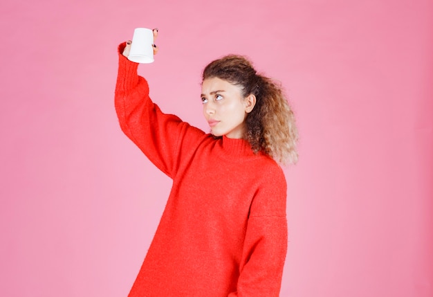 Free photo woman holding a disposable cup upside down.