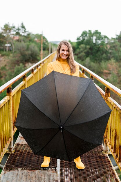 Woman holding down an open black umbrella