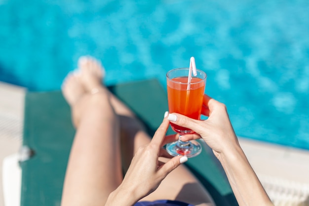 Woman holding drink laying on lounge