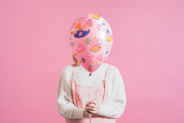 Free Photo woman holding festive balloon on plain pink background