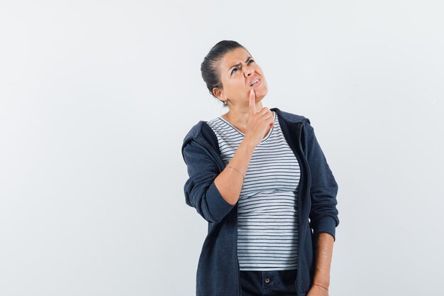 Woman holding finger on chin in t-shirt