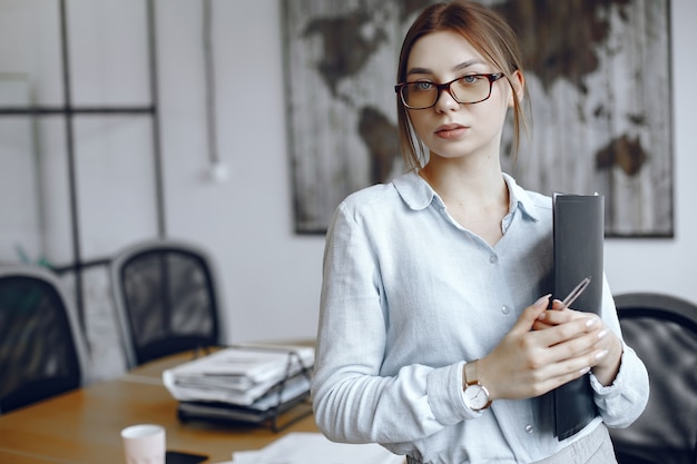 Woman holding a folder.Girl looks at the camera  Beauty in glasses.