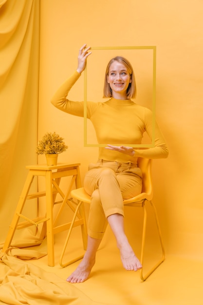 Free photo woman holding frame around face in a yellow scene
