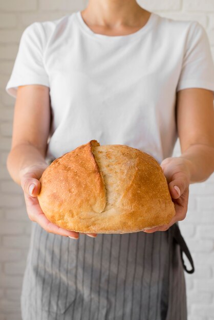 Женщина, держащая свежий круглый хлеб