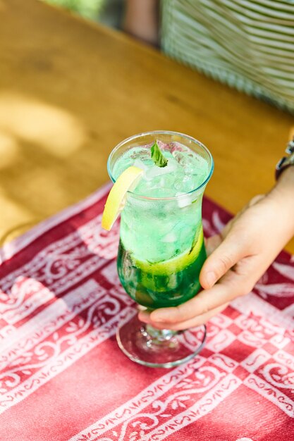 Woman holding a fruit lemonade on wooden table