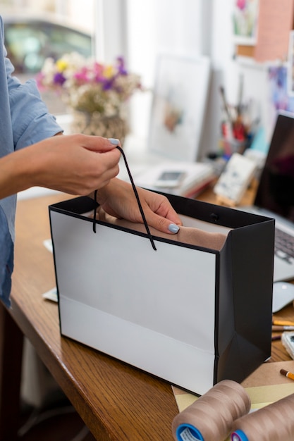 Free photo woman holding gift bag on desk