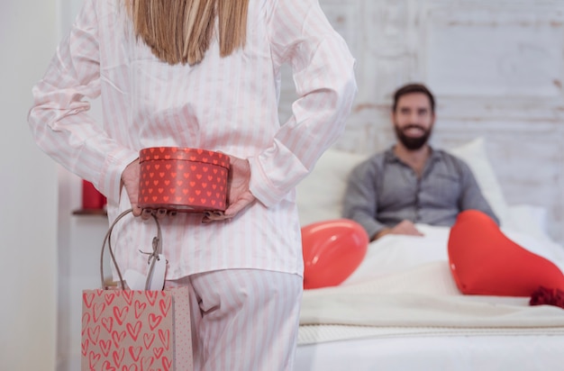 Woman holding gift box behind back