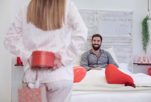 Woman holding gift box for man behind back