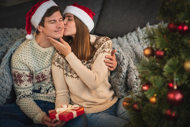 Woman holding gift kissing man