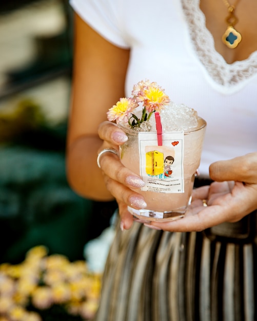 Free photo woman holding a glass of drink with ice decorated with liner from love isgum