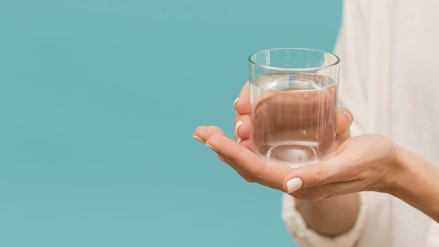 Woman holding a glass filled with water copy space