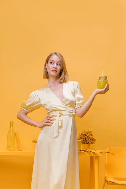 Foto gratuita donna che tiene un bicchiere di limonata nella scena gialla