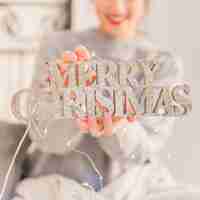 Free photo woman holding glitter merry christmas inscription