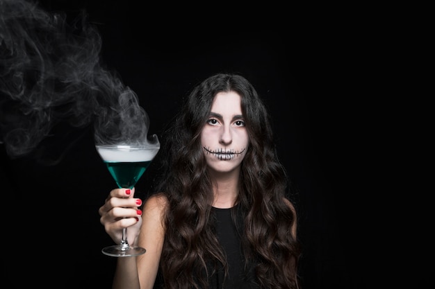 Woman holding goblet with smoking turquoise liquid